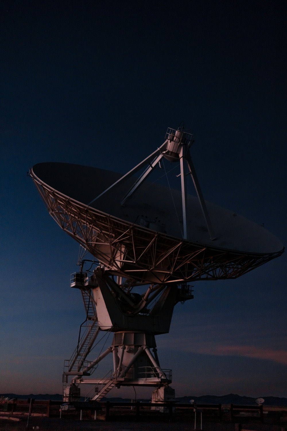 Große Parabolantenne vor dunkelblauem Abendhimmel